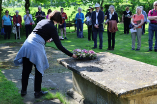 Pilgrimage leader the Revd Carys Walsh laying flowers on the tomb of Nicholas Ferrar: 20 May 2023